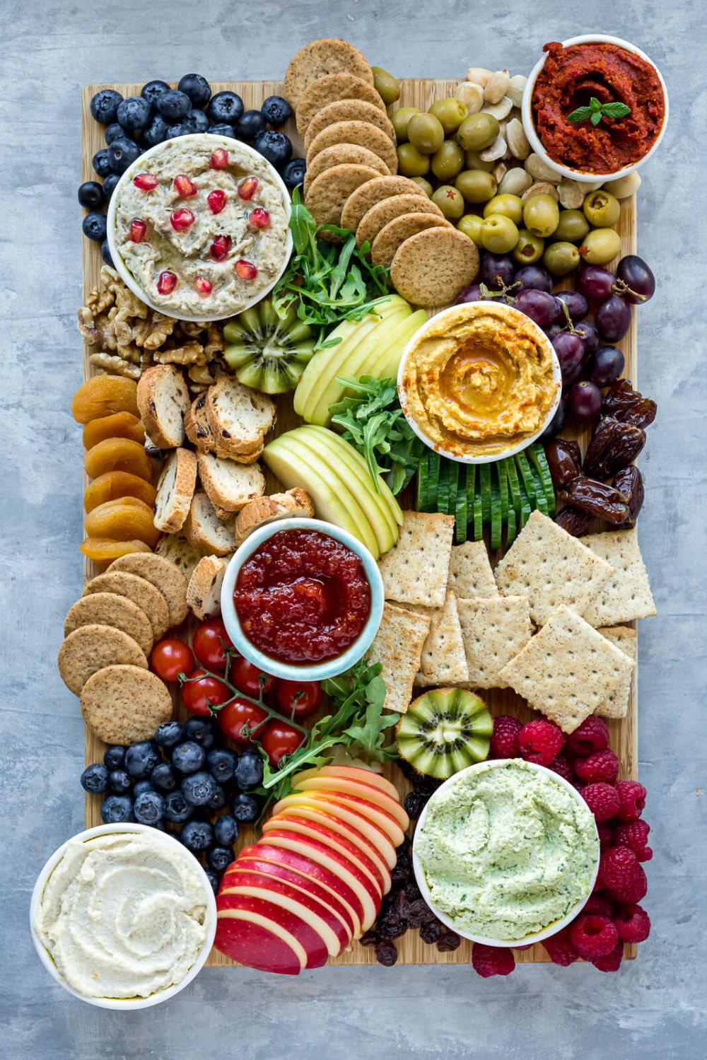 Plant-based charcuterie board with fruits, crackers, nuts, and cheeses